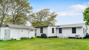 Ein Wohnmobil mit kleiner Garage, einer Terrasse mit Gartenmöbeln und einem Rasen.