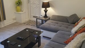 Una sala de estar con un sofá, una mesa de centro, una lámpara, un cuadro y una puerta con un letrero.