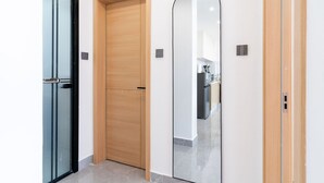 Un pasillo con tres puertas: una de vidrio, una de madera y una espejada.