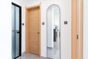 A hallway with three doors: a glass door, a wooden door, and a mirrored door. - Riara Paradise View Palace Apartment (Nairobi)