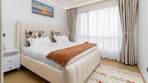 Un dormitorio moderno con cama, mesitas de noche, una lámpara de noche, un cuadro y un ventanal con cortinas.