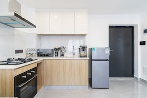 Une cuisine moderne équipée d’un four encastré, d’un réfrigérateur et de meubles de rangement en bois.