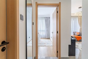 Una habitació d'hotel moderna amb una porta de fusta, un llit amb un estotxa estampat, un sofà amb coixins i un escriptori amb una làmpada.