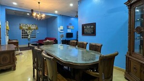 A dining area with a large glass-top table surrounded by wooden chairs, a ceiling fan, and a chandelier.
