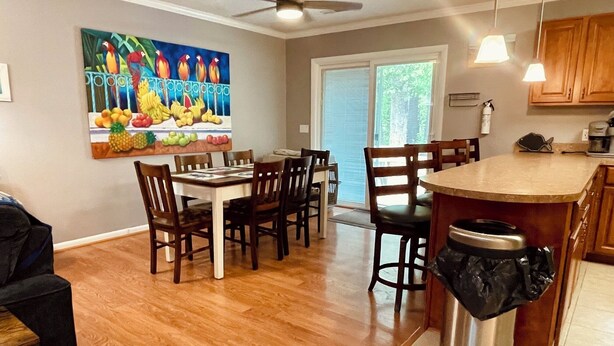 A kitchen with wooden cabinets, a dining table with chairs, a ceiling fan, and a painting on the wall. - Offshore Tails, Relax with your pets in Ocean Pines, Near OCMD.  No pet fee! (Ocean Pines)