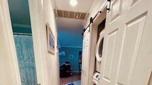 A laundry room with a washing machine and dryer, a tiled floor, and a hallway leading to a dining area. - Offshore Tails, Relax with your pets in Ocean Pines, Near OCMD.  No pet fee! (Ocean Pines)