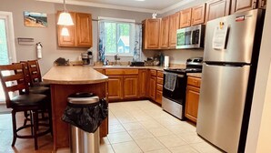 A kitchen with wooden cabinets, a stainless steel refrigerator, a microwave, and a stove. - Offshore Tails, Relax with your pets in Ocean Pines, Near OCMD.  No pet fee! (Ocean Pines)