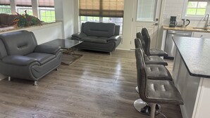 Een moderne woonkamer met een bank, een salontafel en een keuken met een aanrecht en spoelbak.