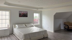 Een slaapkamer met een bed, twee ramen, een plafond met bloemenprint en een stoel in de hoek.