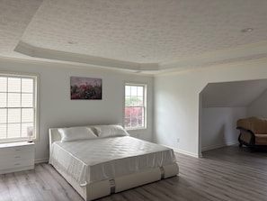 A bedroom with a bed, two windows, a ceiling with a floral pattern, and a chair in the corner.