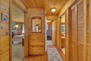 Ein Holzblockbau-Innenraum mit einer zentralen Tür, einem Bett, einer Küchenzeile und einem Badezimmer.