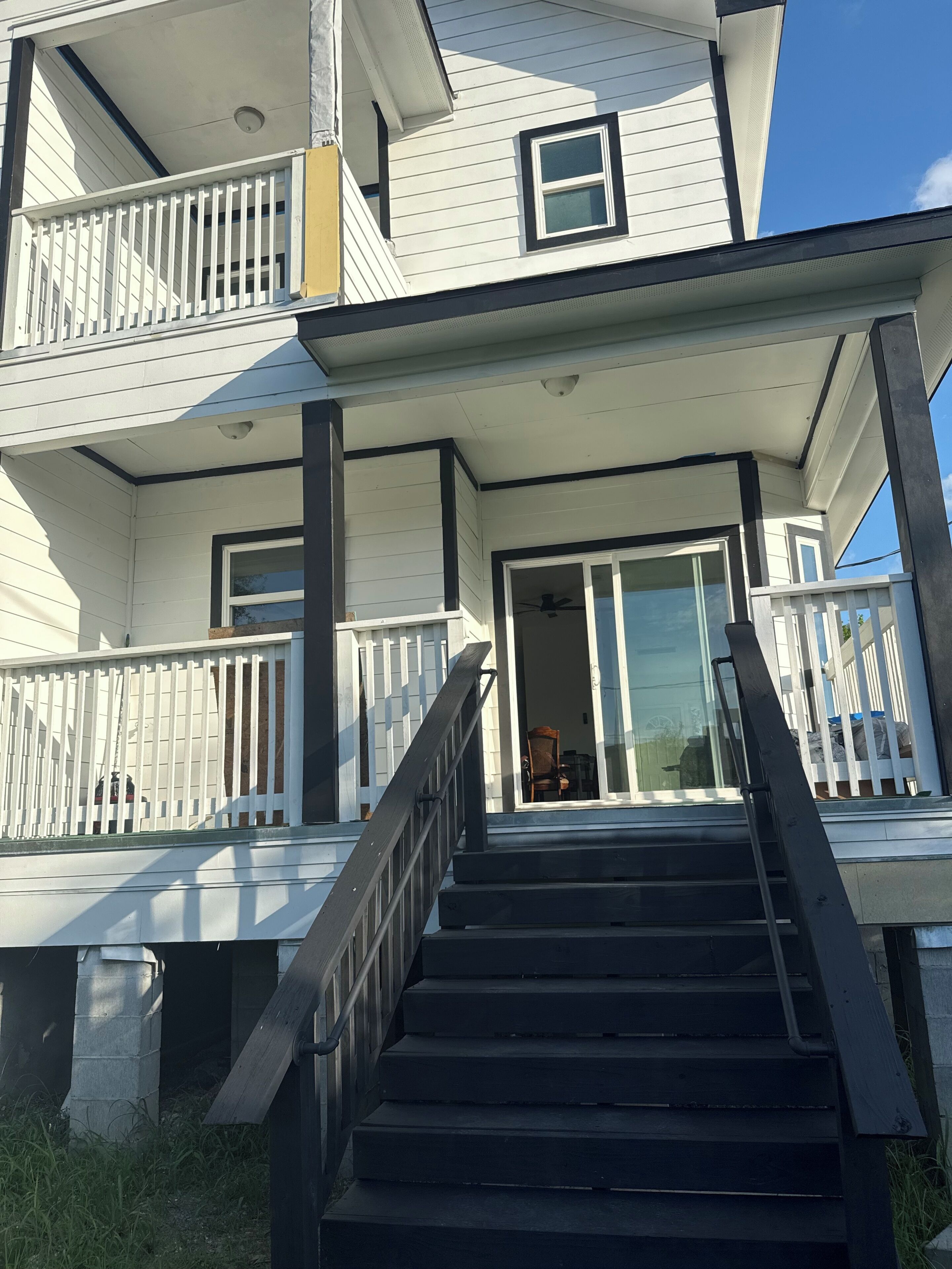 A two-story building with a balcony, a staircase leading to the entrance, and a visible door.