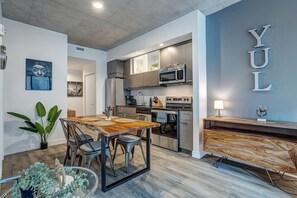 A modern kitchen with stainless steel appliances, a dining area with a wooden table and chairs, and a wall with the letters 'YUL' displayed. - Montreal - C Lofts Le Smith 2 Bedroom (Montreal)