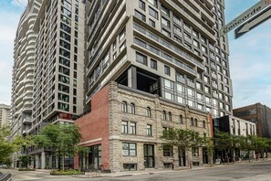 A multi-story building with a mix of modern and classical architecture, featuring a prominent corner entrance and a visible ground-level commercial space. - Montreal - C Lofts Le Smith 2 Bedroom (Montreal)