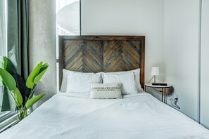 Et hotelværelse med en seng, et træhovedgærde, et natbord, en lampe og en plante.