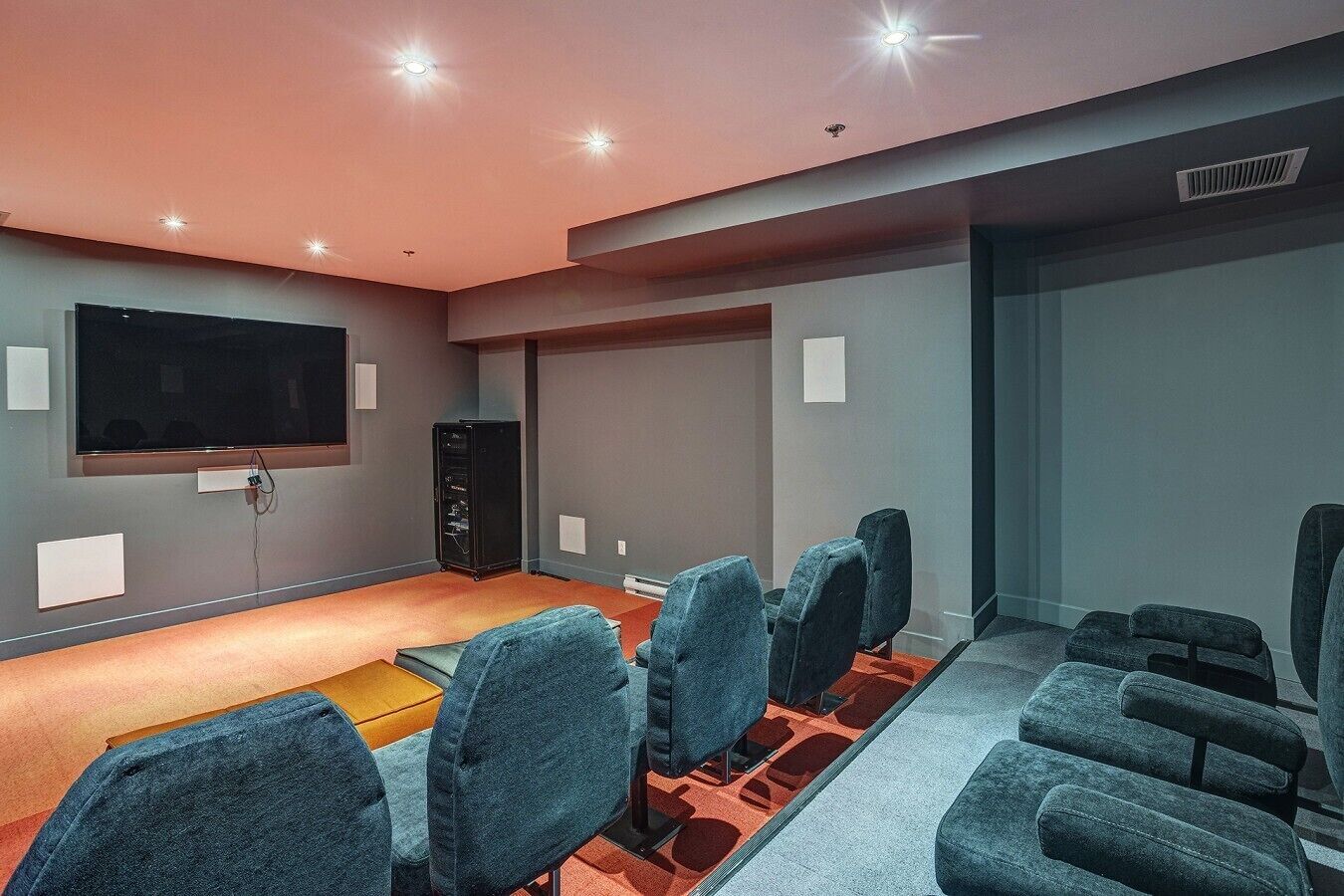 Ein Kino mit Sitzreihen, einer großen Leinwand und einer Tonanlage.