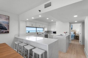 A modern kitchen with a large island, bar stools, and a view to the sea. - Oceanfront, Penthouse,Pool, Hot Tub, Elevator, Beach Service Included (Miramar Beach)