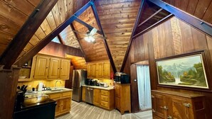 Un interior de madera con cocina, un refrigerador, un microondas y un cuadro en la pared.