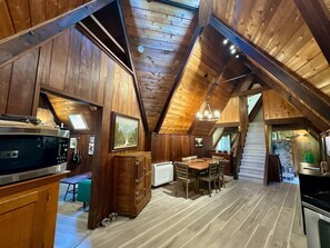 A wooden interior with a kitchen, dining area, and staircase.