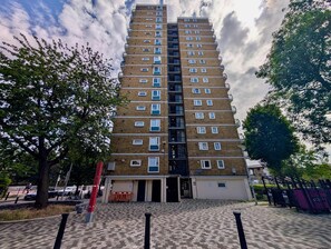 A multi-story residential building with a brick facade, multiple windows, and a gated entrance. - 1bed Near Stratford with Breathtaking City Views (London)