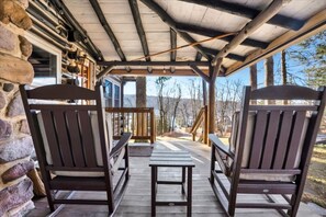 A wooden deck with two Adirondack chairs and a small table, overlooking a scenic view. - Lake View ~ Authentic Log Cabin ~ Spruce Lodge (Albrightsville)