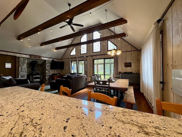 A spacious living area with a large granite island, a fireplace, and a dining table with chairs.