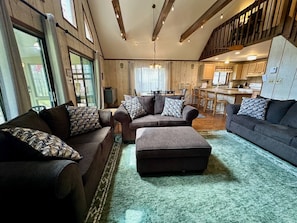 A spacious living room with a large sofa set, a coffee table, and a dining area with a chandelier.