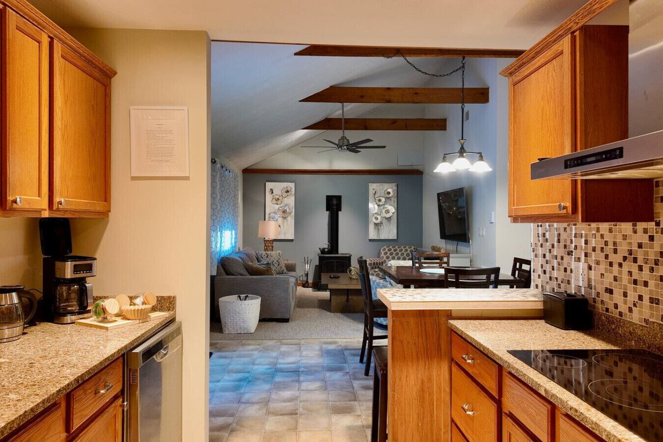 Una cocina con armarios de madera, estufa integrada y comedor con mesa y sillas.