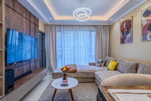 Ein modernes Wohnzimmer mit Flachbildfernseher, einer Couch, einem Couchtisch und Kunstwerken an den Wänden.