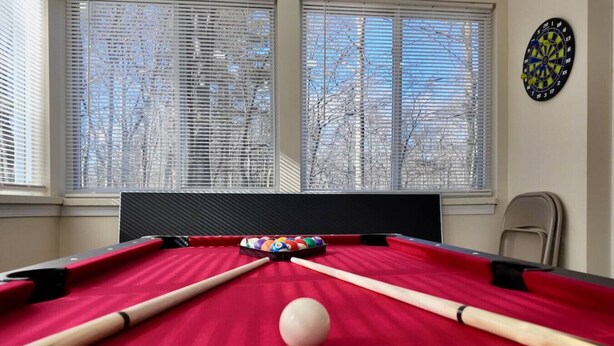 A pool table with balls and cues, a dartboard, and a window with blinds. - Hot Tub ~ Luxury Landing (Tobyhanna)