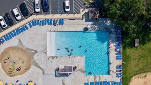 An aerial view of a swimming pool area with lounge chairs, a small beach, and a parking lot. - Hot Tub ~ Luxury Landing (Tobyhanna)