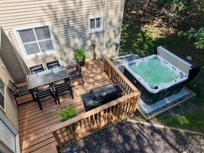 Una terraza con jacuzzi, mobiliario exterior y una mesita.