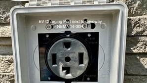 Une borne de recharge pour véhicules électriques située à côté d’une allée, équipée d’une prise NEMA 14-30R.