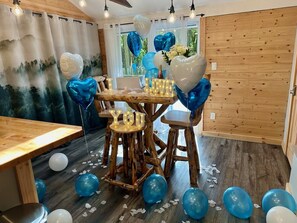 A room with a wooden table and chairs, balloons, and a 'I LOVE YOU' sign. - Romantic A-Frame - Hot Tub - Pets Welcome (Blakeslee)