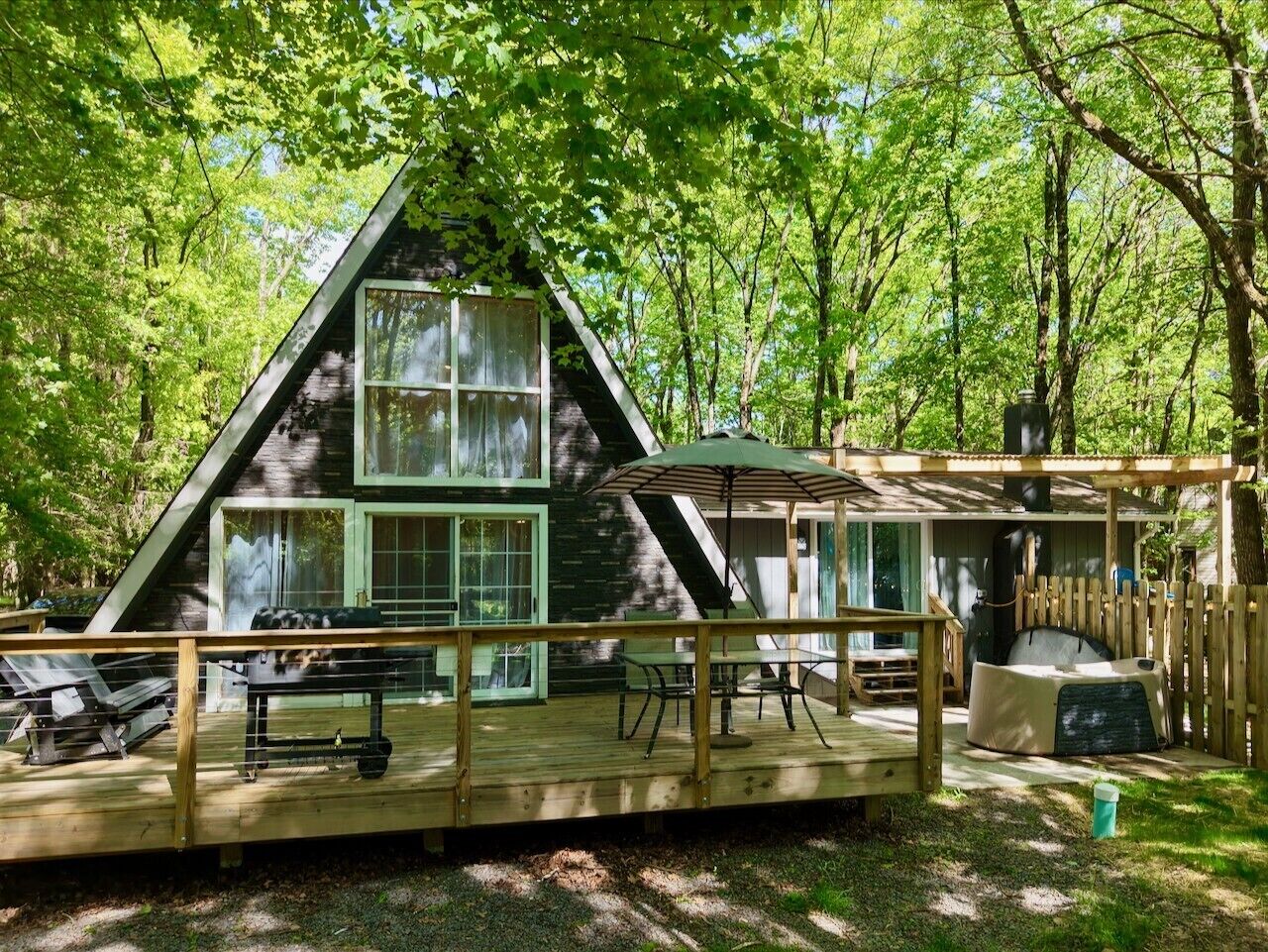 Une cabane dotée d’une terrasse, d’un espace extérieur couvert avec des sièges et d’une grande fenêtre.