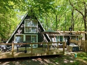 Eine Hütte mit einer Veranda, einem überdachten Sitzbereich und einem großen Fenster.