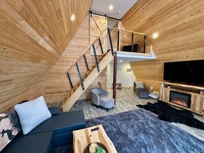 Ein gemütliches Interieur mit einer Holztreppe, einer Couch, einem Fernseher und einem Kamin.