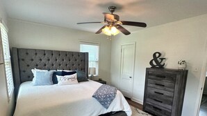 Une chambre à coucher avec un lit, un ventilateur de plafond, une commode et un tapis.