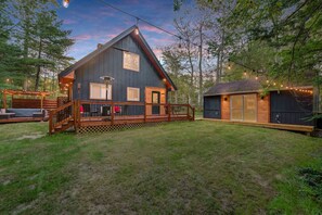Eine Hütte mit einer Terrasse, einer Garage und Lichterketten.