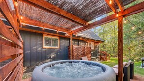 Een hottub in een houten buitenruimte met een pergola erboven.
