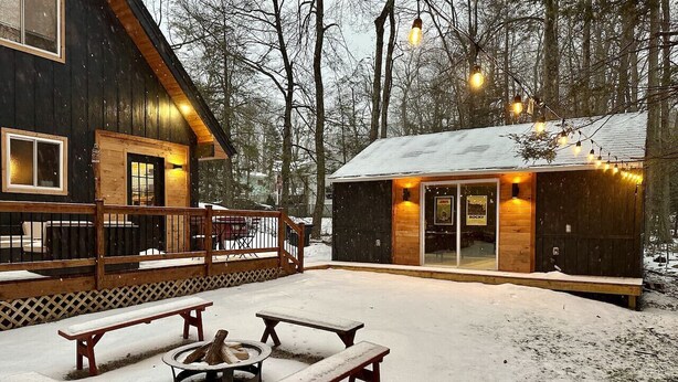 A cabin with a deck, outdoor seating, and a fire pit.
