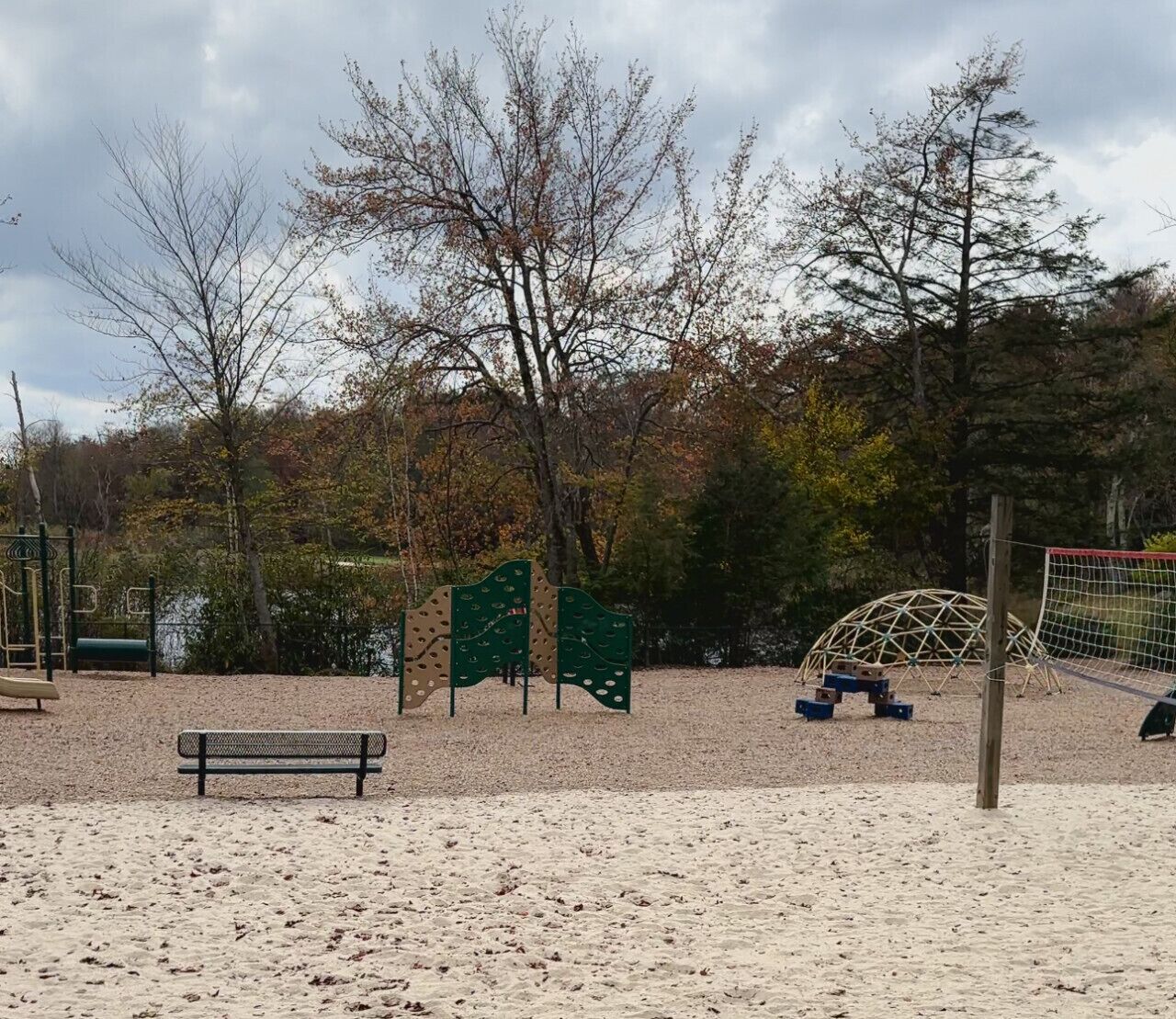 Une zone de plage sablonneuse avec un banc, des structures d’escalade et une petite structure en forme de dôme.