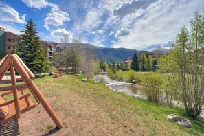 A riverside view with a playground, trees, and buildings in the background. - Pet Friendly Hotel Room in Central Copper MTN! (Frisco)