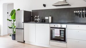 Une cuisine moderne avec des armoires blanches, une hotte de cuisinière en acier inoxydable et un porte-couteaux suspendu.