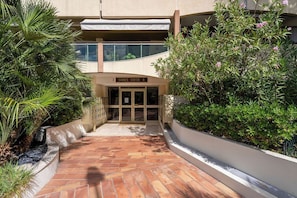 A building entrance with a sign reading 'Cannes Center A,' surrounded by greenery and a tiled pathway. - L'Aparté Cannois avec balcon en centre-ville (Cannes)