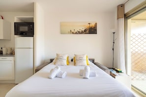A hotel room with a bed, pillows, towels, a painting, a microwave, and a refrigerator. - L'Aparté Cannois avec balcon en centre-ville (Cannes)