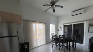 A kitchen with a refrigerator, a ceiling fan, a dining table with chairs, and a sliding glass door.