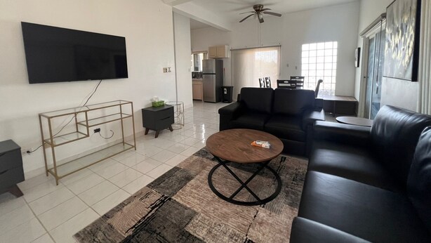 A living room with a sofa, coffee table, TV, and a ceiling fan.