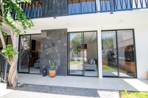 Et moderne hus med en stenvæg, store skydedøre af glas og et synligt udendørs opholdsområde.