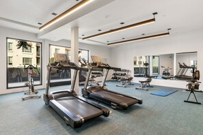Ein modernes Fitnessstudio mit Laufbändern, Crosstrainern und Kurzhanteln.